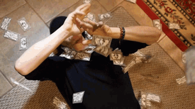 a man is laying on the floor with a lot of money flying around him