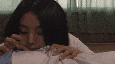 a woman laying on a bed with her hands on her chest