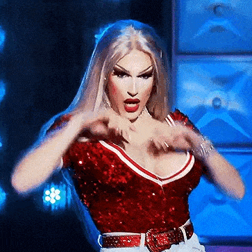 a drag queen is wearing a red sequined top and a belt .