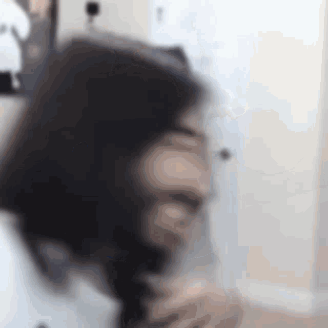 a blurry picture of a man with long hair and a beard holding a glass of wine .