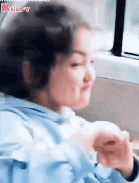a little girl is sitting in the back seat of a car and making a funny face .