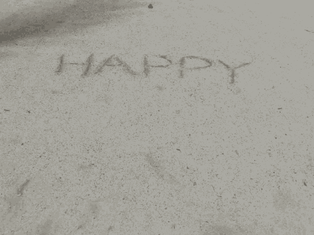 the word happy is written in the sand on a concrete surface