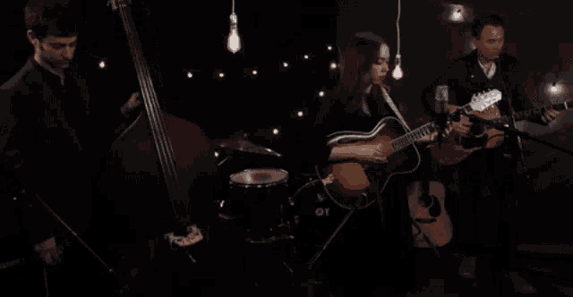 a man playing a double bass a woman playing a guitar and a man playing a guitar