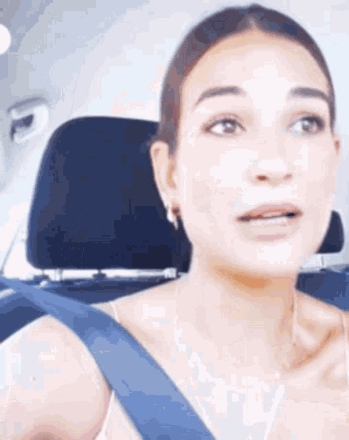 a woman is sitting in the back seat of a car with a blue seat belt around her neck .