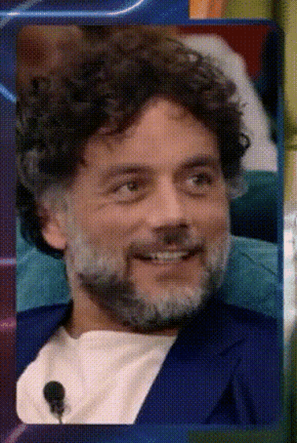a man with curly hair and a beard smiling