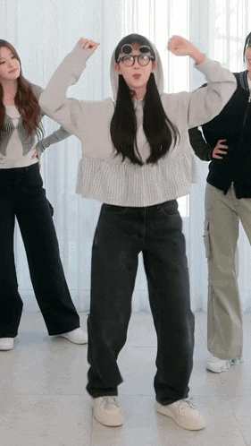 a woman wearing glasses and a hoodie is dancing with other women