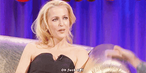 a woman in a black dress is sitting on a couch talking to a man .