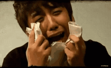 a man is crying while holding a piece of paper in his hands .