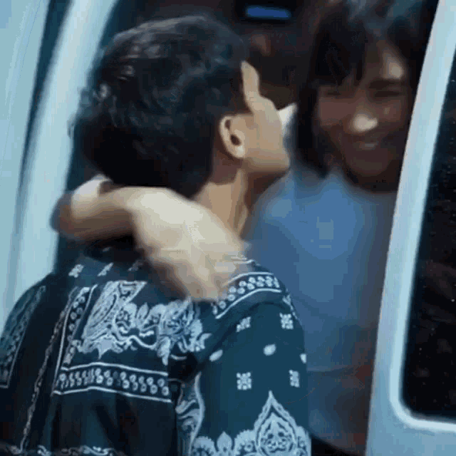 a man in a bandana shirt is hugging a woman in a white car .
