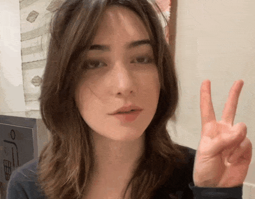 a woman giving a peace sign in front of a sign that says o