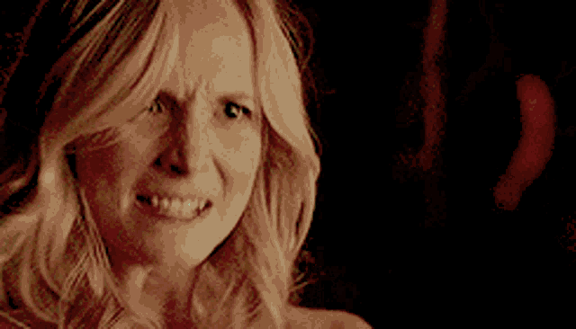 a woman without a shirt is making a funny face in the dark .