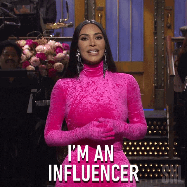 Kim Kardashian in a pink dress hosting SNL with the caption "I'm an influencer."