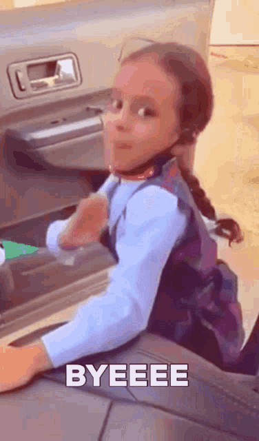 a little girl is sitting in the back seat of a car with the word byeee on the bottom