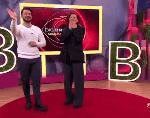 a man and woman are dancing in front of a sign that says bigbr