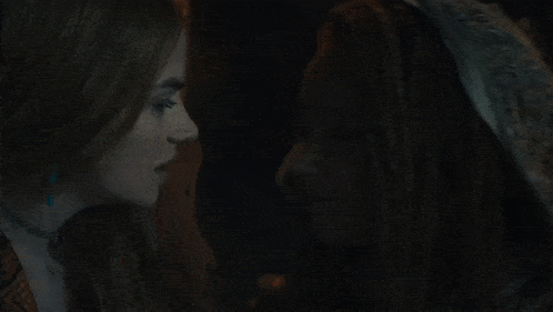 a woman with dreadlocks kisses another woman in a hooded hat