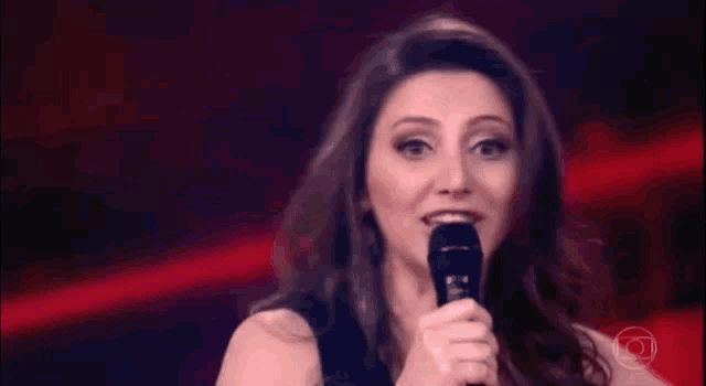 a woman is holding a microphone and smiling while standing on a stage .