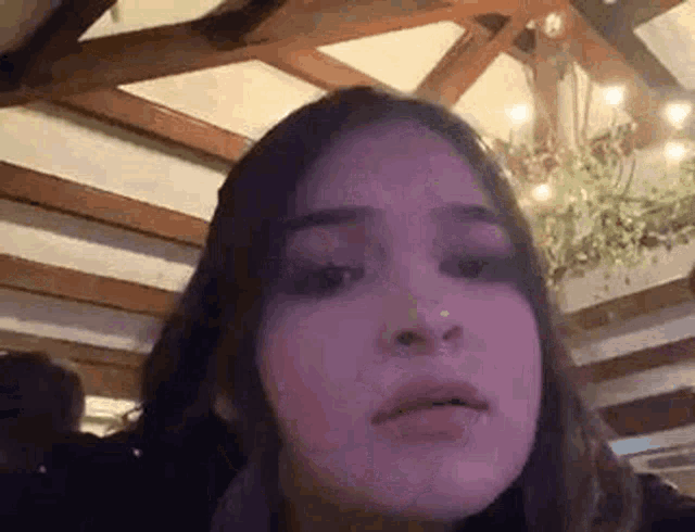 a girl is sitting in a room with a chandelier and looking at the camera .