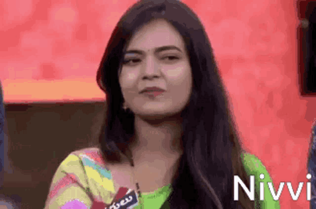 a woman with long hair is wearing a green and yellow striped shirt and looking at the camera .