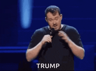 a man is holding a microphone and making a funny face while standing on a stage .