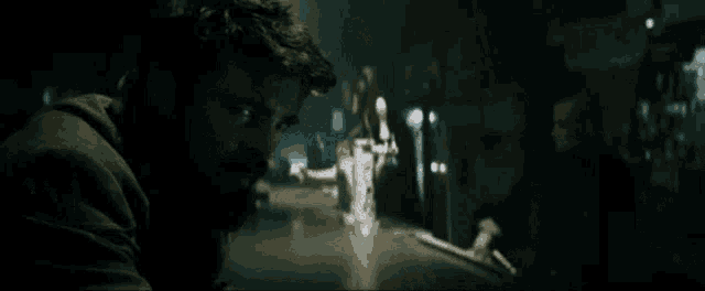 a man with a beard looks at the camera in a dark room with a sign that says ' coca cola '