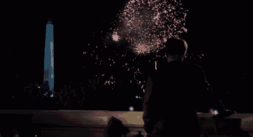 a man stands in front of a fireworks display with the washington monument in the background