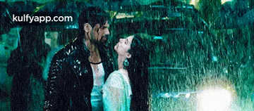 a man and a woman are kissing in the rain with the website kulfyapp.com in the corner .