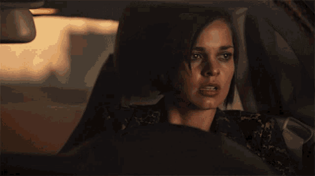 a woman is sitting in a car holding her head