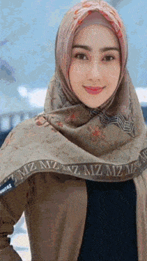 a woman wearing a hijab and a scarf with the letter m on it