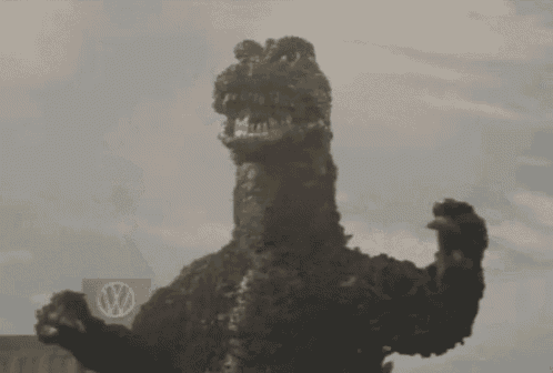 a statue of a monster is standing in front of a building with its arm up in the air .