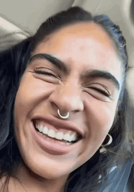a close up of a woman 's face with a nose ring and earrings .