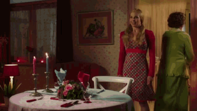 a woman in a red dress stands in front of a table