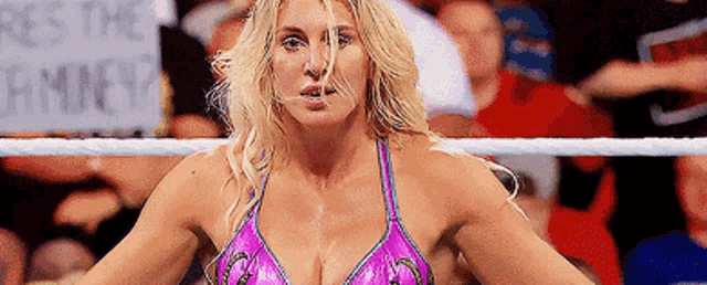 a woman is standing in a wrestling ring with a sign in the background .