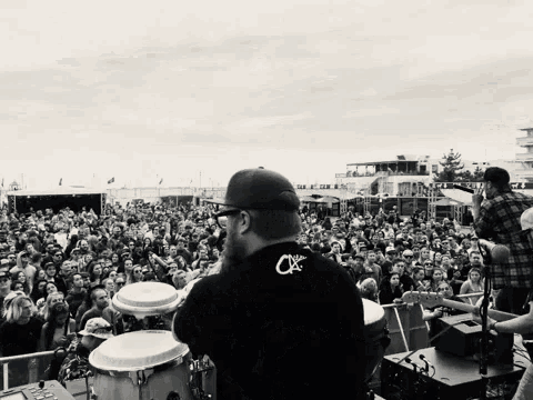 a man wearing a black shirt with the letter cx on the back stands in front of a crowd