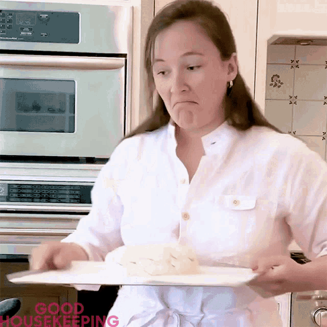 a woman in a white shirt is holding a white plate with the words good housekeeping on the bottom