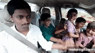 a man is sitting in the back seat of a car holding a group of children .