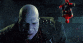 a bald man with purple eyes is standing next to a spider man