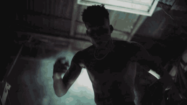 a shirtless man in a dark room with smoke coming from the ceiling