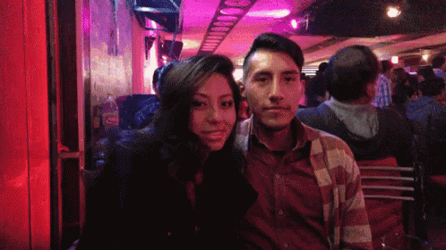a man and a woman are posing for a picture in a crowded bar