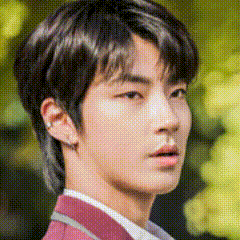 a close up of a young man 's face with a blurred background and a red jacket .