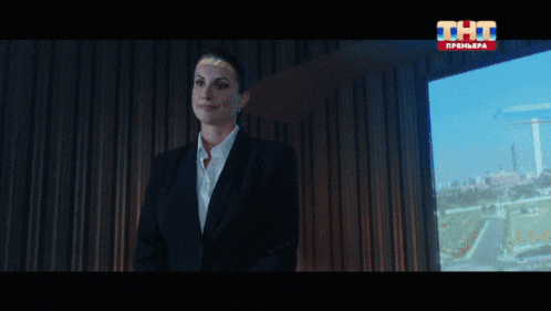 a woman in a suit is standing in front of a window that says tht on it