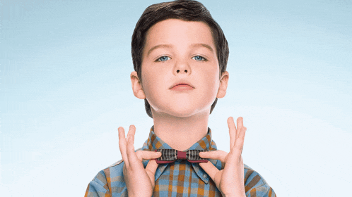 a young boy wearing a bow tie is making a wish