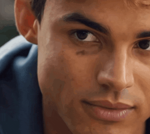 a close up of a man 's face with a blue shirt