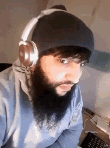 a man with a beard wears headphones and a beanie