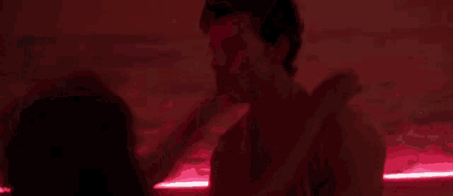 a man and a woman are hugging each other in a dark room with red lights behind them .