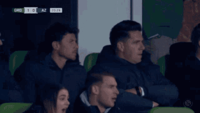 a group of people in a stadium watching a soccer game and the score is 1-0