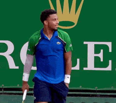 a man is holding a tennis racket in front of a rolex sign