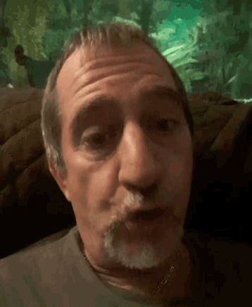 a man with a beard is sitting on a couch with his mouth open