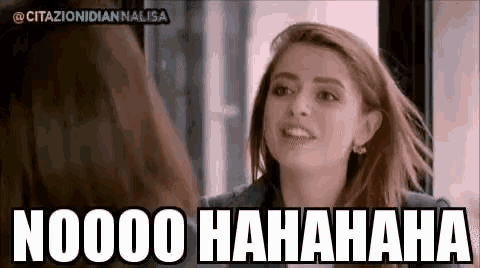 a woman is laughing and looking at herself in the mirror while another woman looks on .