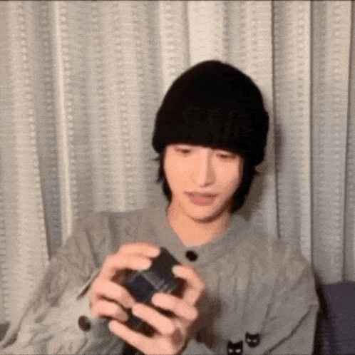 a young man wearing a black hat and a sweater is holding a box in his hands .