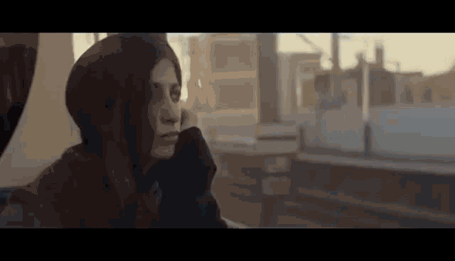 a woman is sitting on a train looking out the window at the city .